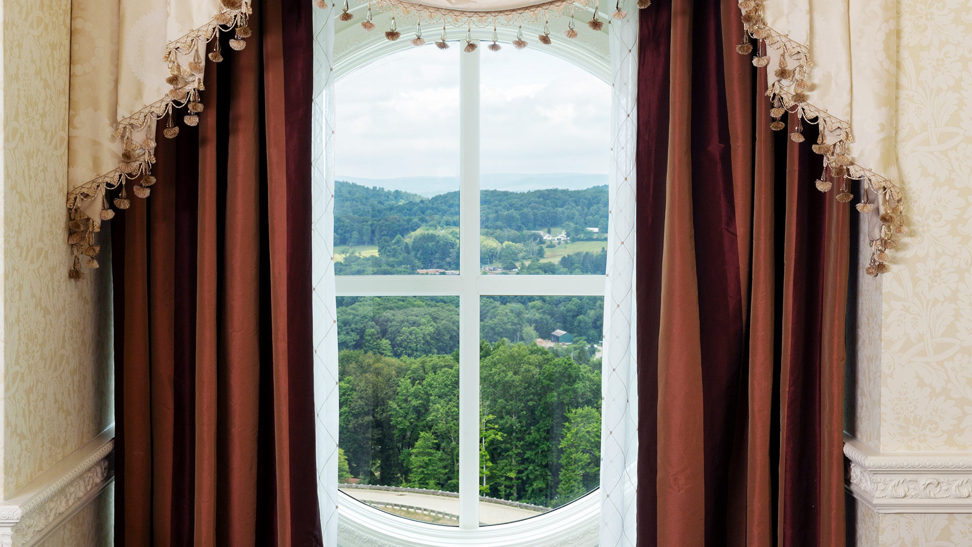 large window overlooking the resort grounds. beautiful red and white curtains frame the window