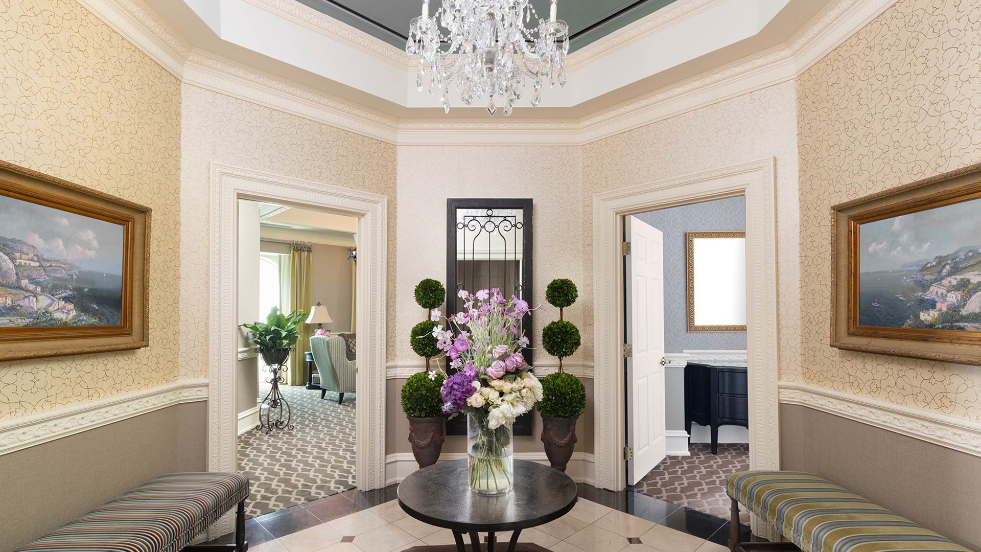 interior shot of The Chateau's presidential suite foyer. There is a round table in the center with flowers. on either side is a door leading to another room.