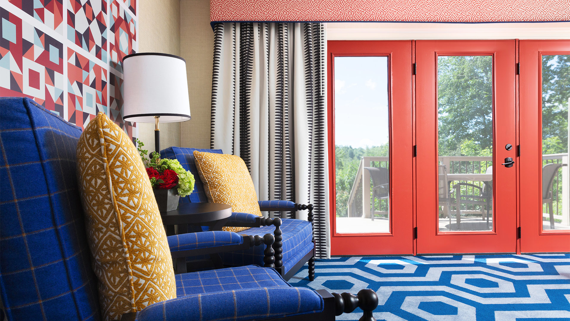 interior shot of a Washington townhome sitting area. There is a blue geometric rug, two blue chairs with yellow pillows. The room has red accents along the door and in some artwork behind the chairs.