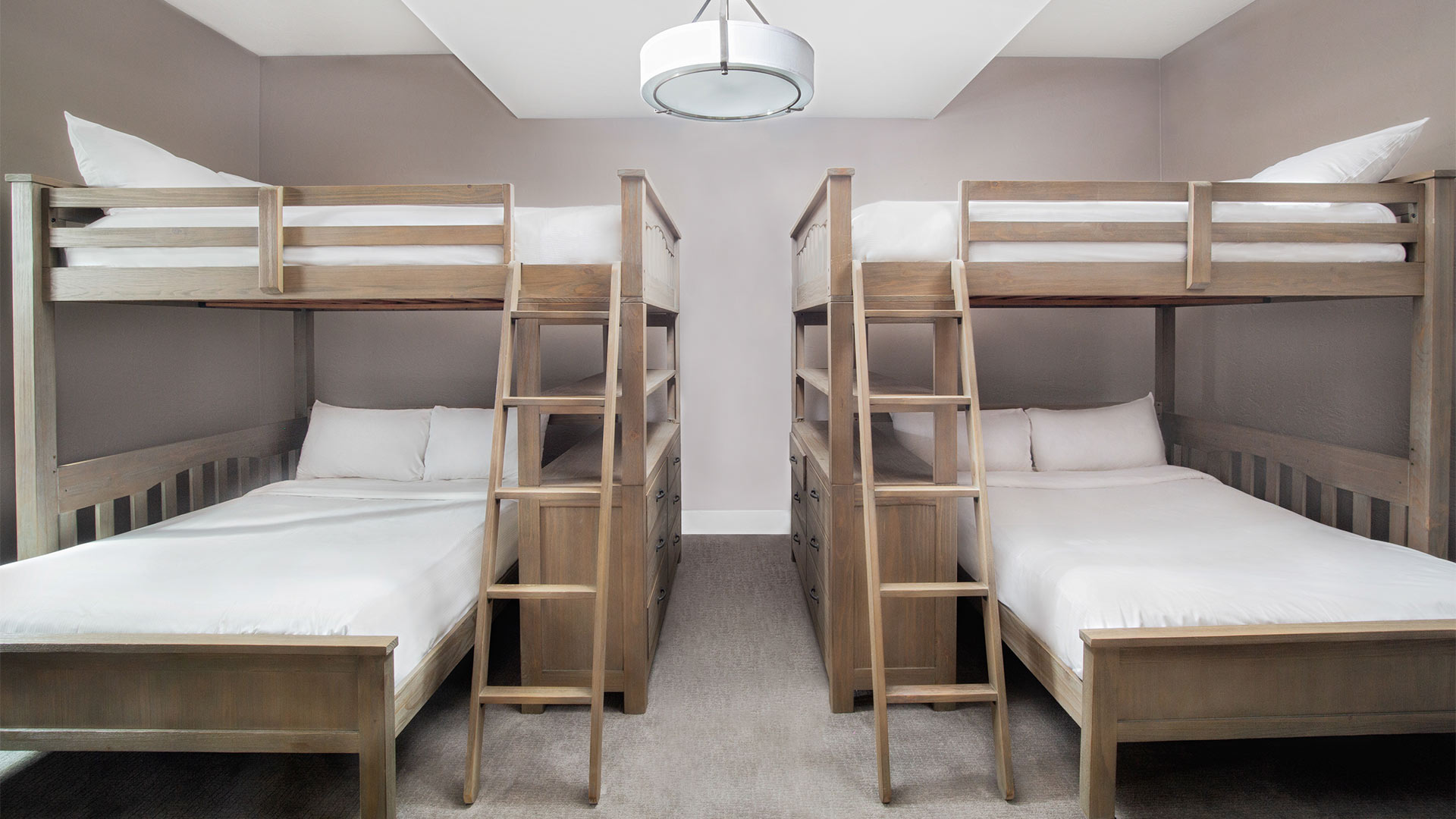 interior shot of a dogwood bedroom with two bunk beds on either side of the room. Each bed has all white linens