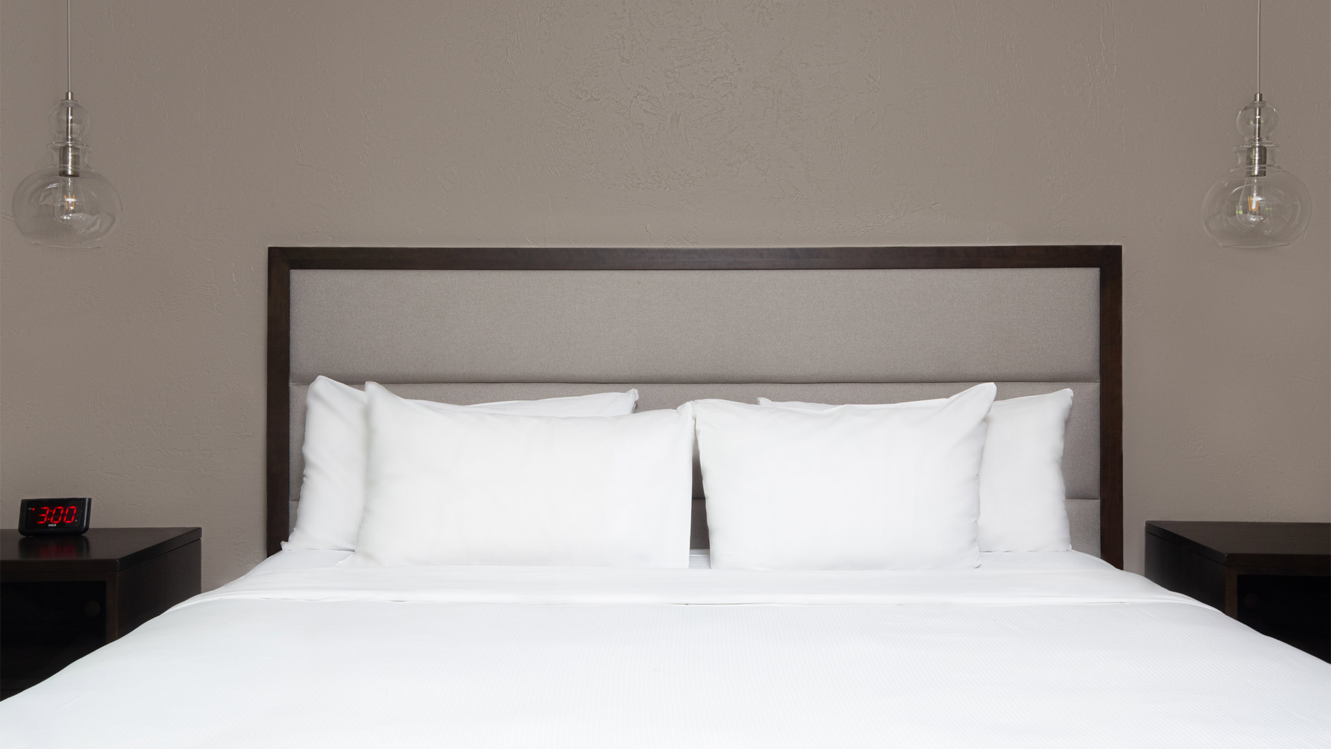 detail shot of a bed with all white linens and bed side tables on either side of the bed