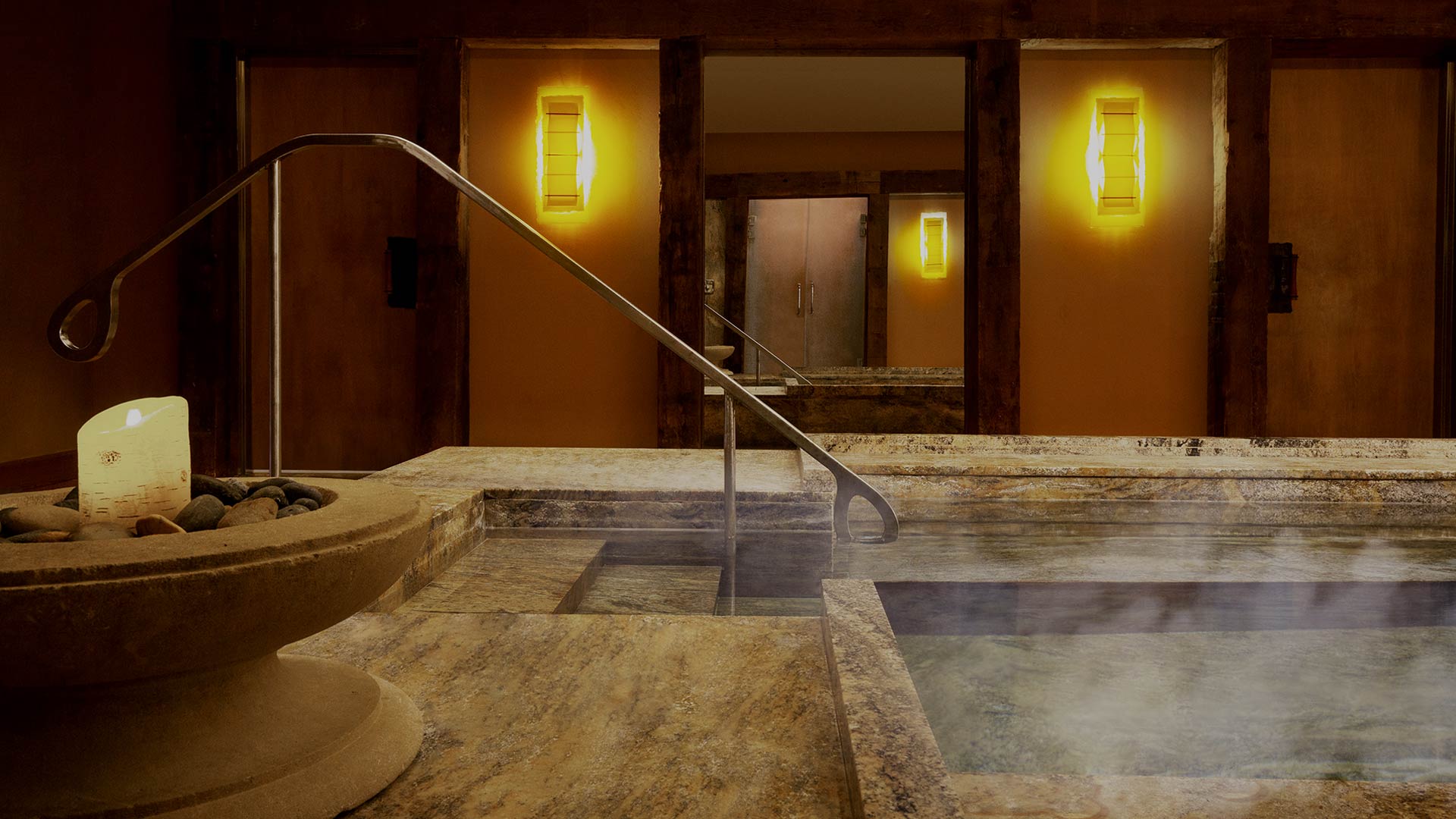interior shot of a spa hot tub. there is soft lighting, lit candles and steam rising from the hot tub