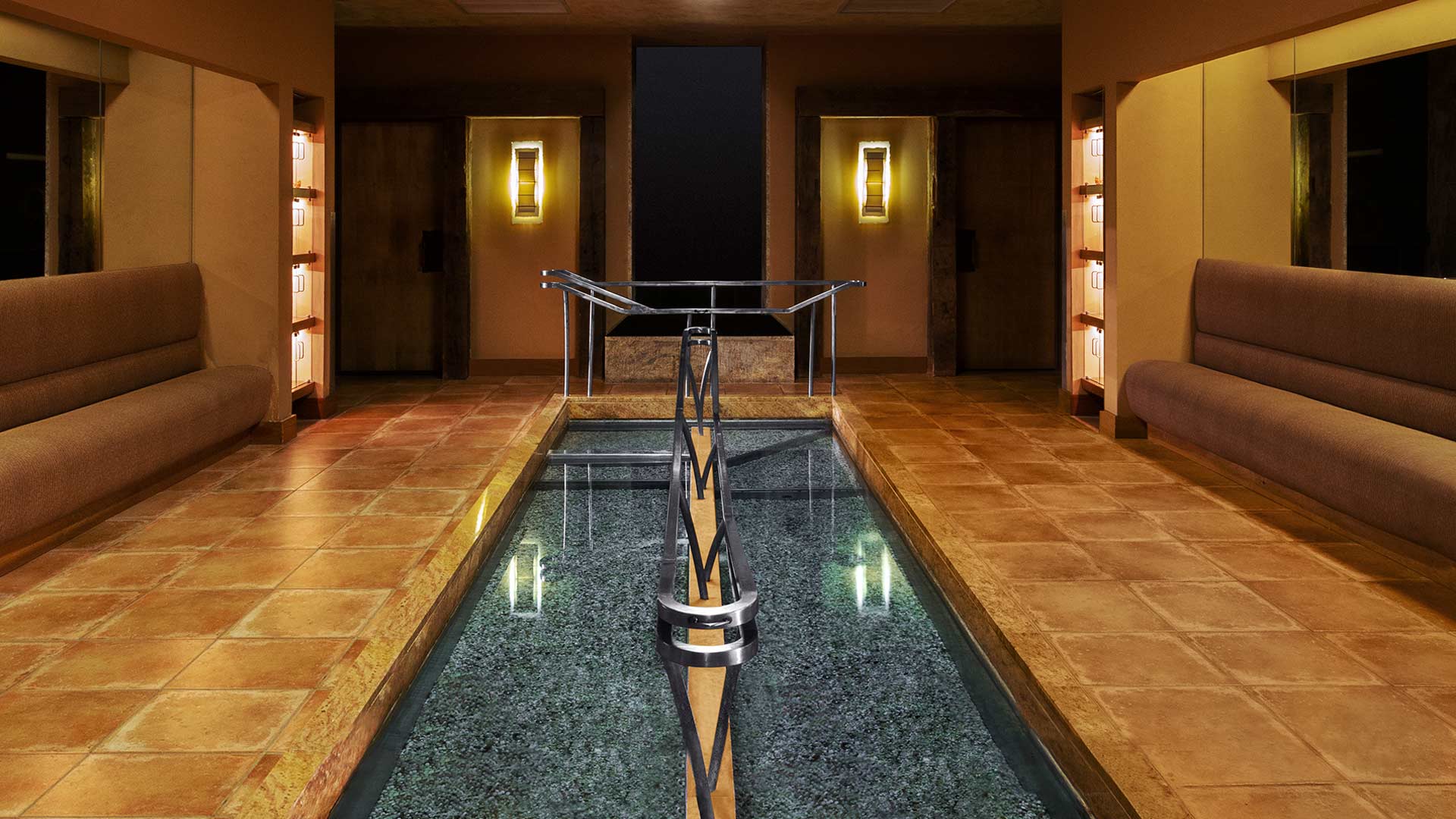 dark, warming interiors surround a thin, long dipping pool