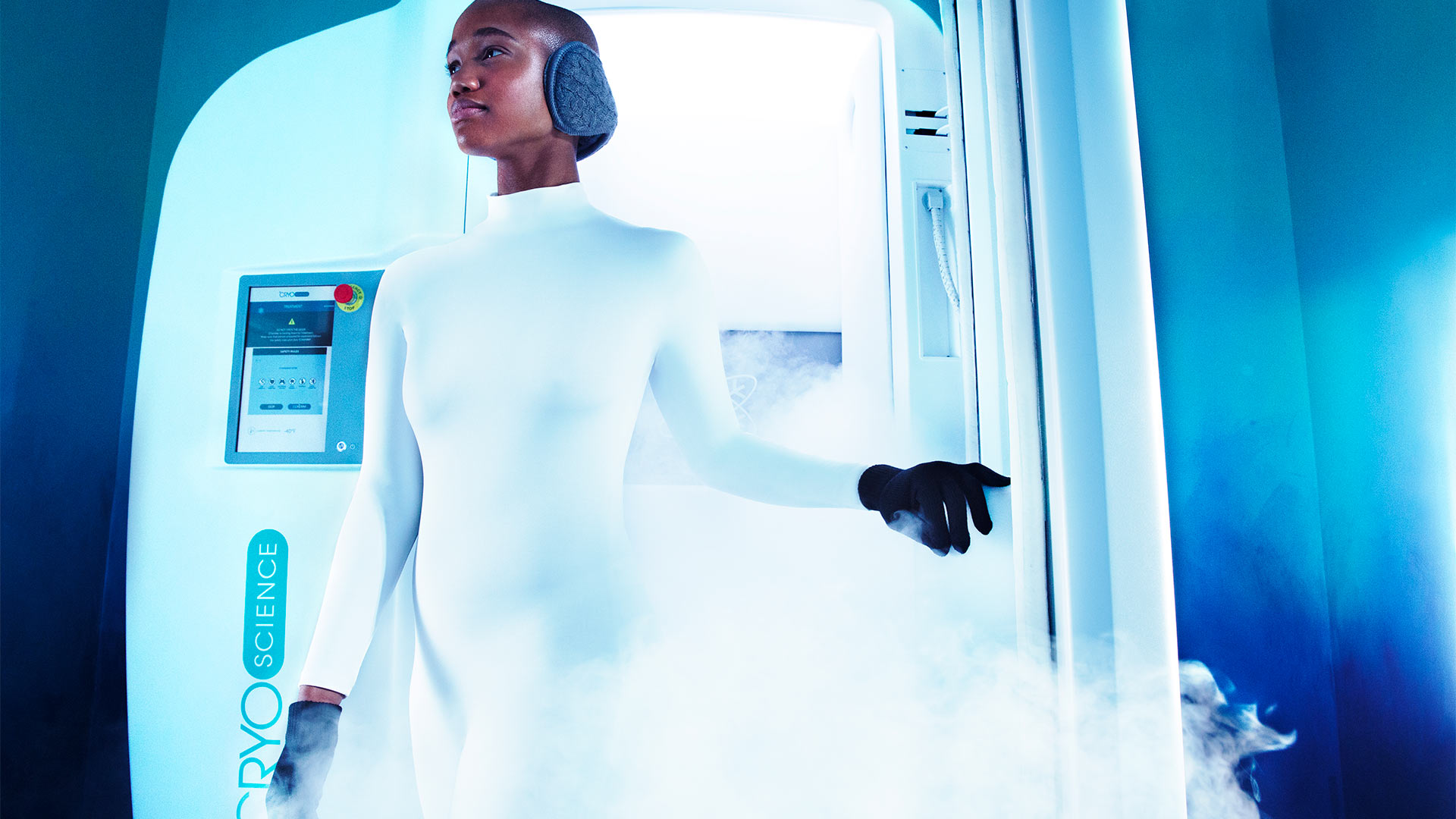a woman in a futuristic white jumpsuit is walking out of a steam chamber
