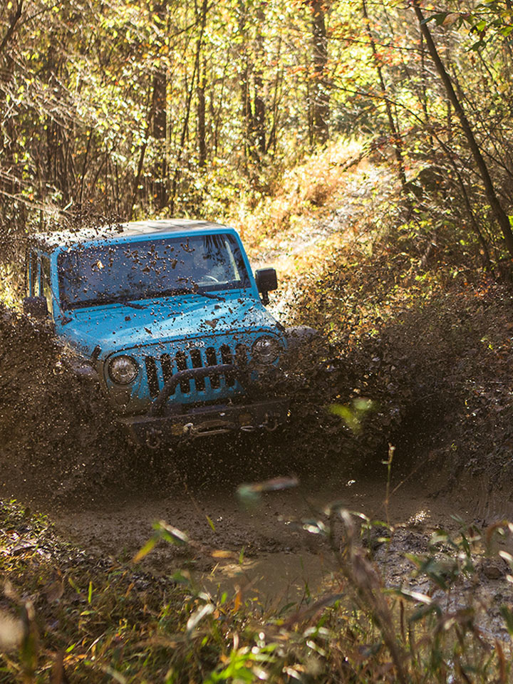 blue jeep driving into mud
