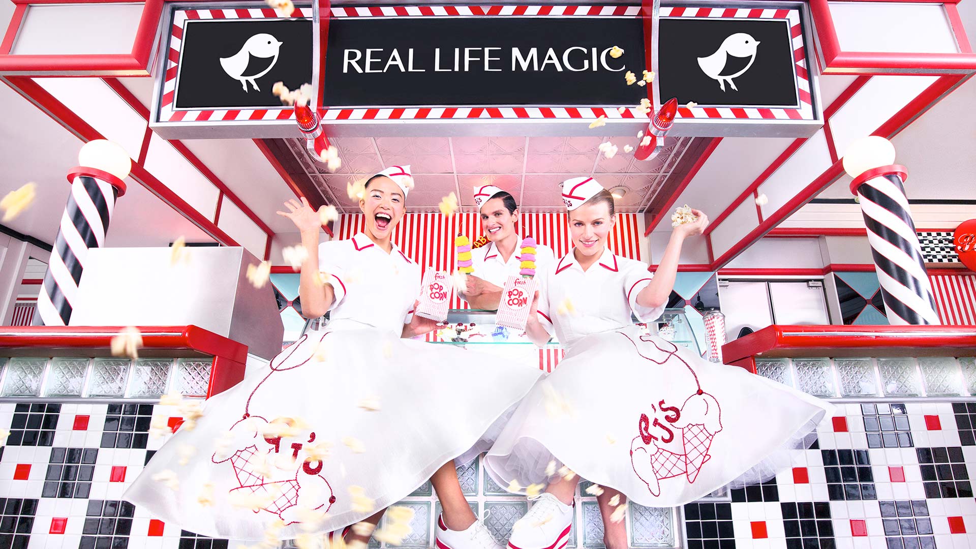 "Real Life Magic" sign above three girls in big skirts and hats serving ice cream