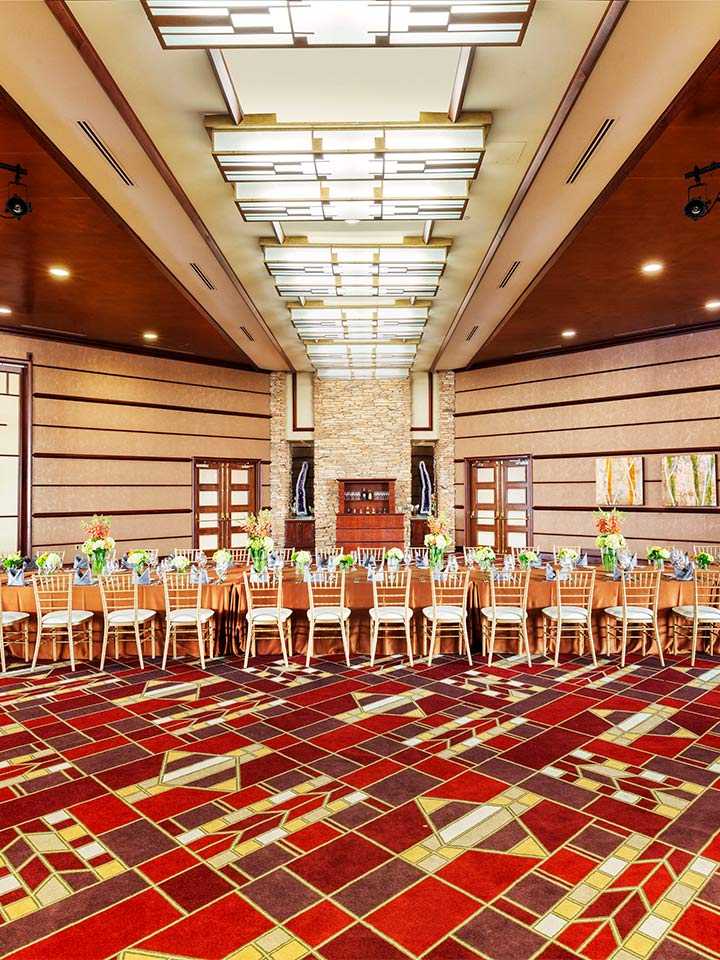 large room with red patterned carpet and tables with chairs