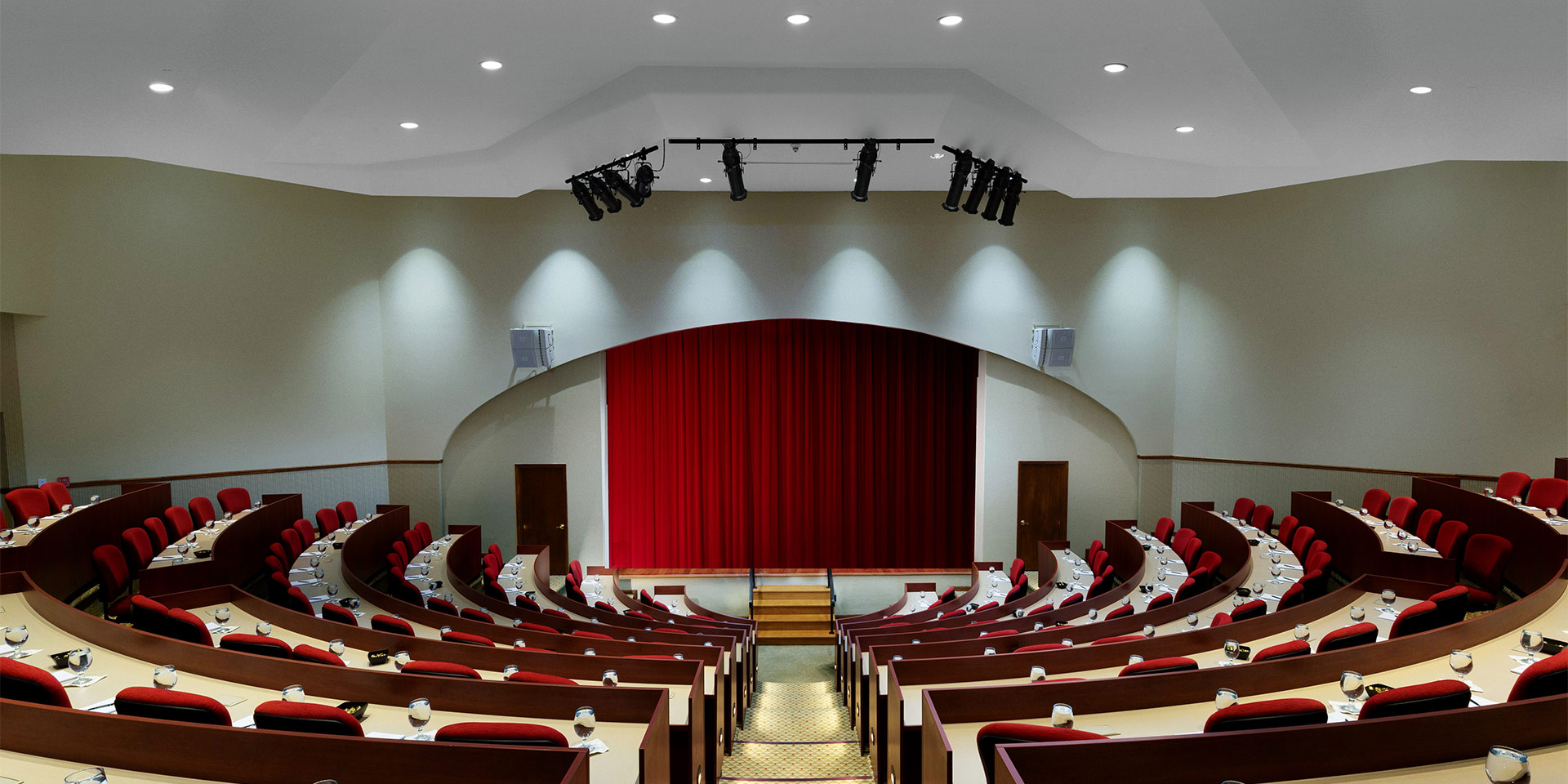 small auditorium with red curtain covering the stage