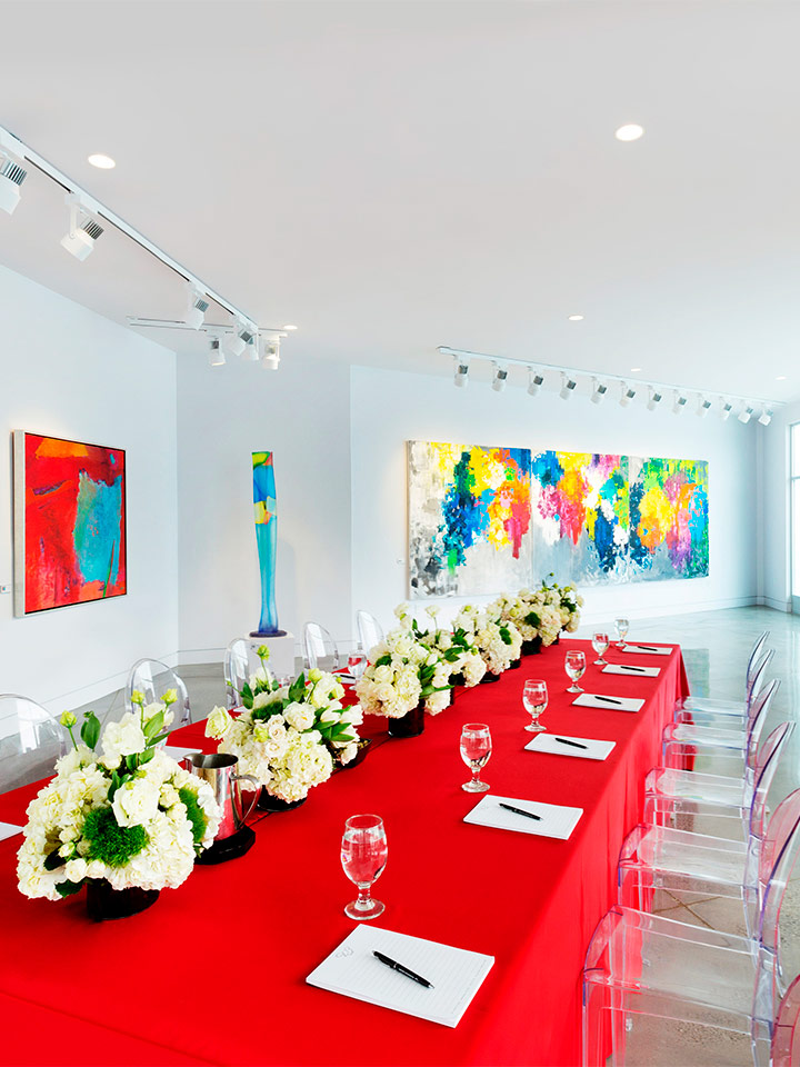 gallery style room with art on the walls and large dining table with red table cloth