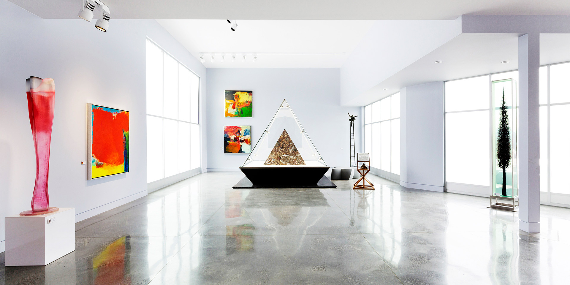 gallery style room with art and large glass pyramid sculpture in the middle
