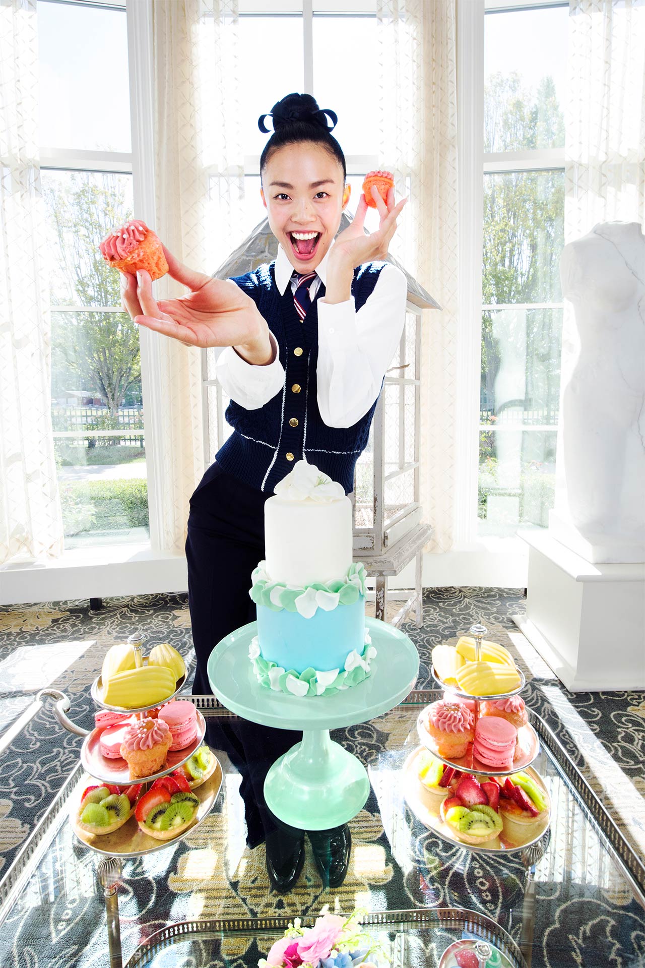 Waitress holding up cupcakes and standing behind a table of desserts