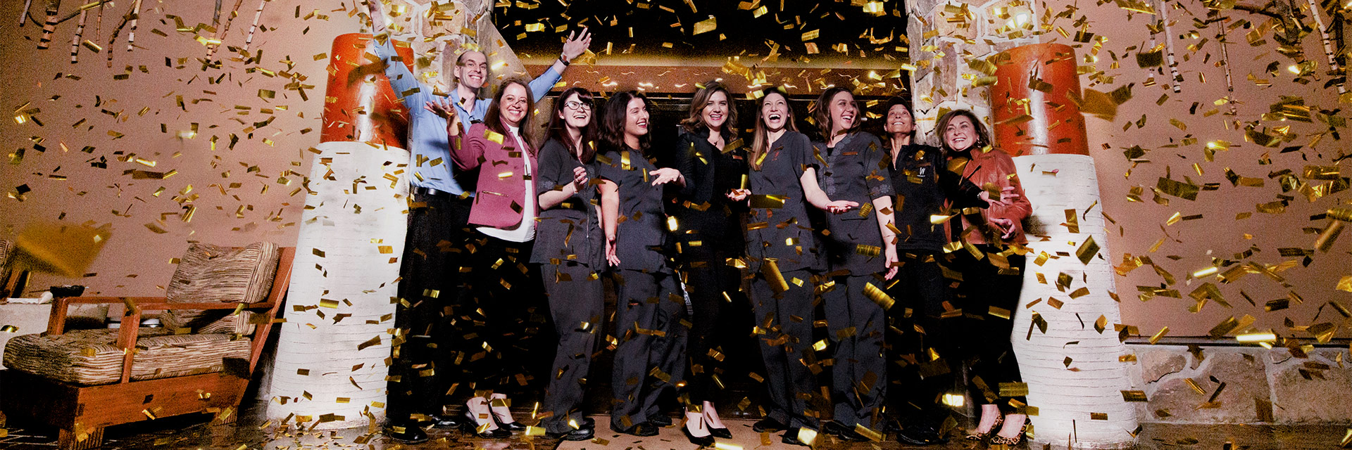 A group of women standing and smiling with confetti in the air