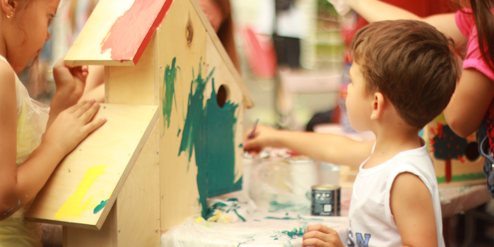 Kids painting a a wooden house.